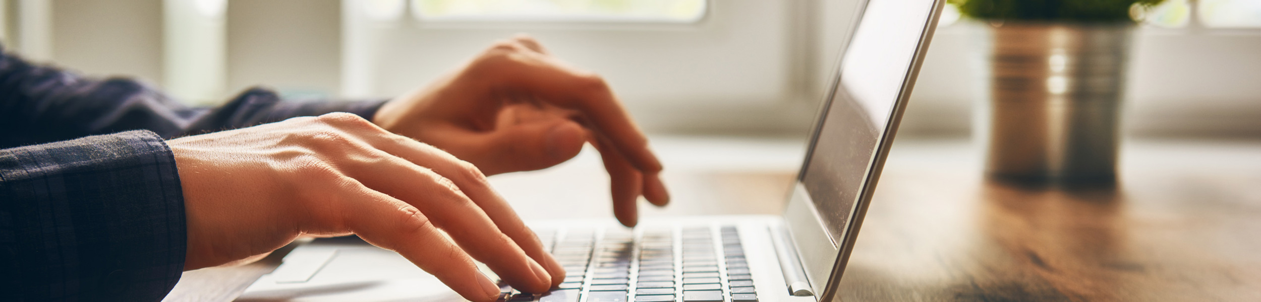 Ein Notebook mit sichtbaren Händen einer Person welche dies bedienen