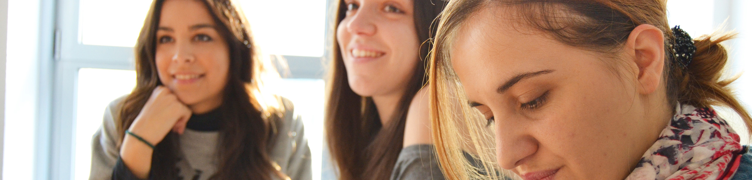 Drei junge Frauen, welche sehr interessiert jemand zuhören